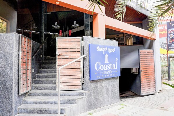 A hotel entrance with a sign for Coastal Grand Hotel & Resorts, featuring a staircase and a gated entrance.