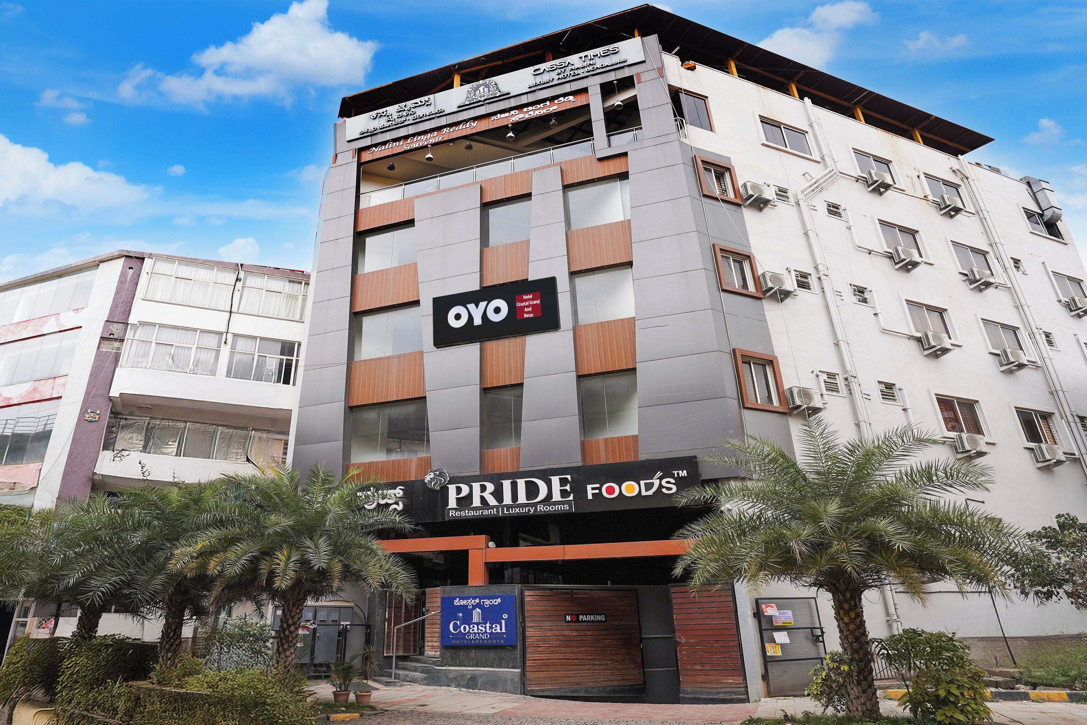 Un edificio de hotel con varios pisos, un letrero destacado de 'OYO' y un restaurante 'PRIDE FOODS'.