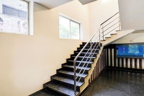A staircase with a metal handrail, leading to a landing with a window.