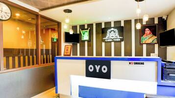 A reception desk with a 'NO SMOKING' sign, a television, and framed awards on the wall.
