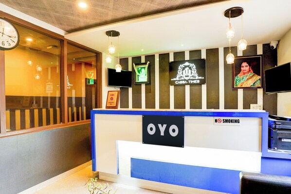 Una recepción con un letrero de 'NO FUMAR', un televisor y premios enmarcados en la pared.
