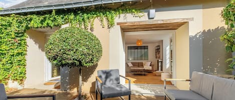 A cozy outdoor seating area with a wooden deck, a gray sofa, and a small table with wine glasses.