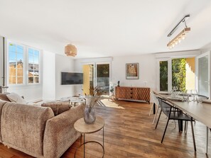 A spacious living area with a sofa, a dining table, and a TV mounted on the wall. - Le Laurier - Centre-ville - Petfriendly (Laval)