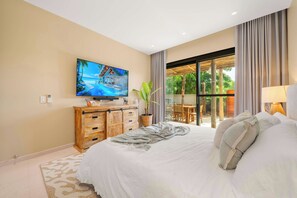A bedroom with a large bed, a television mounted on the wall, a wooden dresser, and a view of the outdoors through a glass door. - 2BR Luxury Escape | Pool, Palapa & Outdoor Shower (Noord)