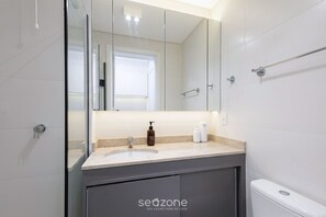 A bathroom with a large mirror, a sink, and a toilet. - Well-located Studio in Condo. Man0603 (Curitiba)