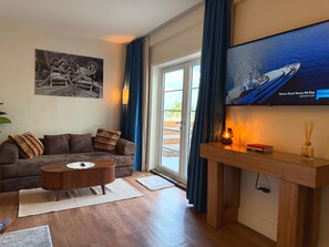 A living room with a sofa, a coffee table, a TV mounted on the wall, and a view of the outdoors through a glass door. - Ocean View Penthouse on Ocean Drive with a Private Pool Oasis (Miami Beach)
