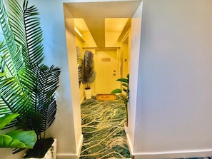 A hallway with a green patterned carpet, a 'hello' mat, and a door labeled 'Penthouse Suite.' - Ocean View Penthouse on Ocean Drive with a Private Pool Oasis (Miami Beach)