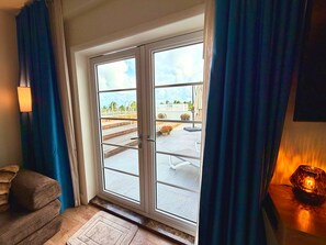 A room with a sliding glass door leading to an outdoor area, a sofa, a lamp, and a rug. - Ocean View Penthouse on Ocean Drive with a Private Pool Oasis (Miami Beach)