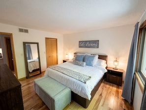 A bedroom with a large bed, bedside tables, a mirror, and a 'lake dreams' sign. - Welcome to the "Cozy Hideout" Charming 3/3 home in the Lake Ariel community. (Lake Ariel)