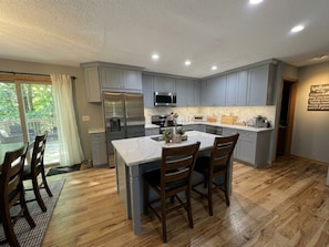 A modern kitchen with grey cabinets, a central island, and a dining area with wooden chairs. - Welcome to the "Cozy Hideout" Charming 3/3 home in the Lake Ariel community. (Lake Ariel)