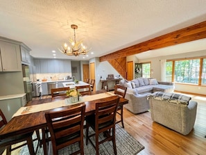 A spacious living area with a dining table, wooden chairs, a sofa, and a large window providing a view of the outdoors. - Welcome to the "Cozy Hideout" Charming 3/3 home in the Lake Ariel community. (Lake Ariel)