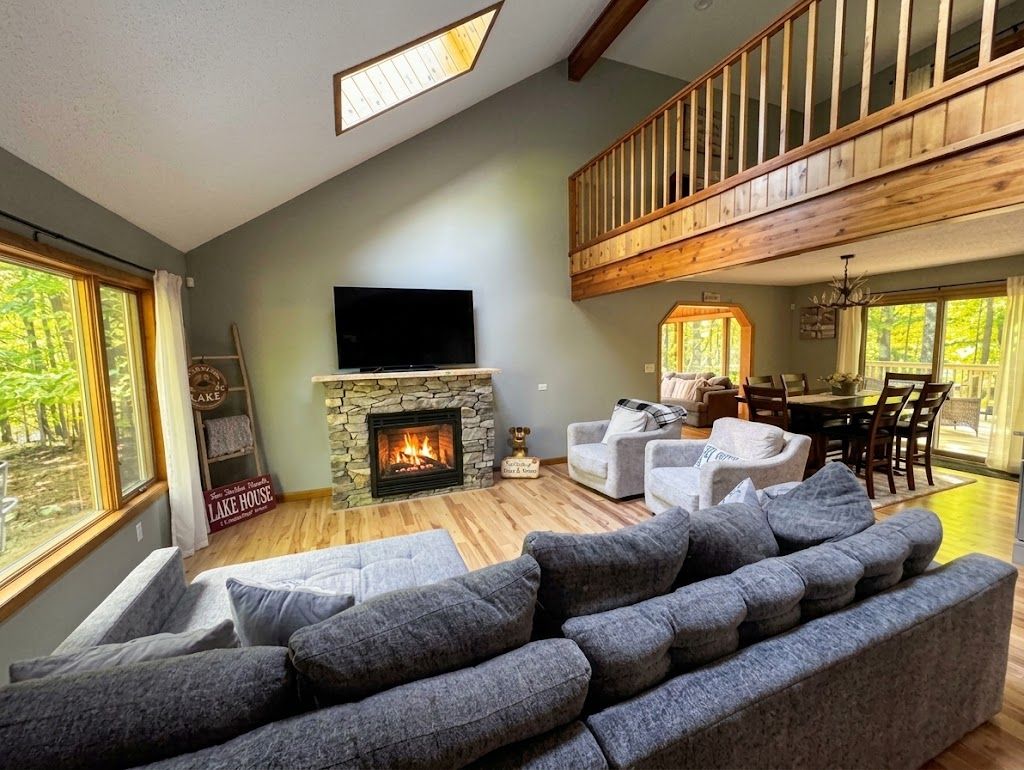 A spacious living room with a fireplace, a television mounted on the wall, and a dining area with wooden furniture.