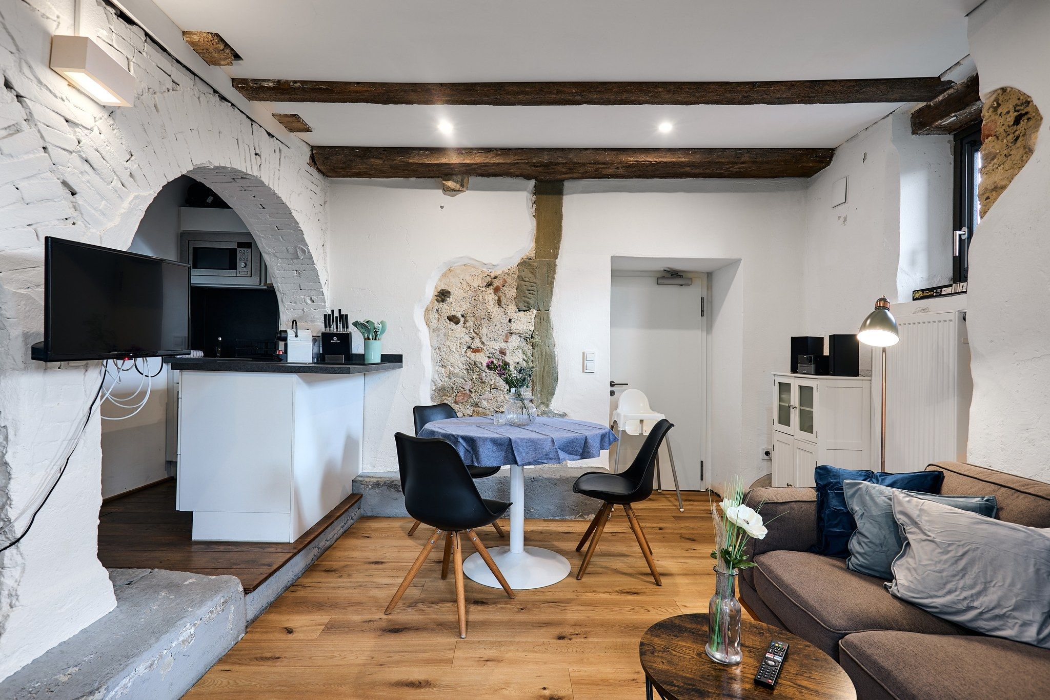 Une cuisine moderne équipée d’un téléviseur à écran plat, d’un coin repas avec une table et des chaises, et d’un salon avec un canapé et une table basse.