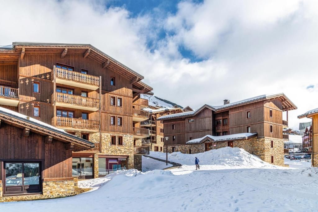 A multi-story wooden building with balconies, a stone foundation, and a snowy environment.