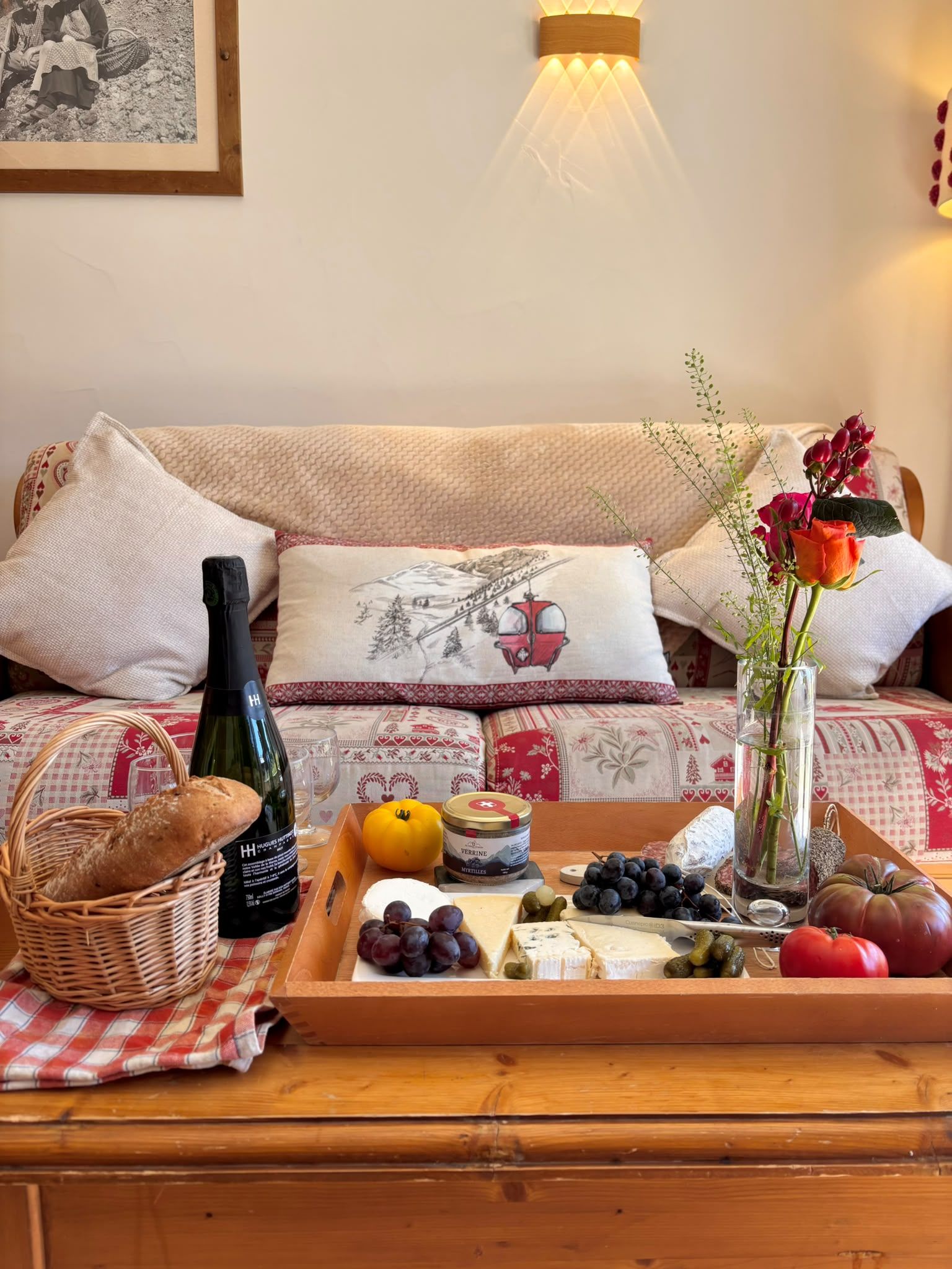 A cozy living room with a sofa, a tray of food, and a bottle of wine.