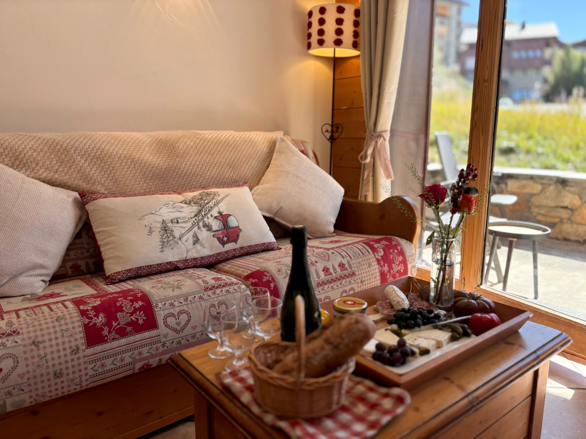 A cozy room with a sofa, a table with a bottle, glasses, and a fruit platter.