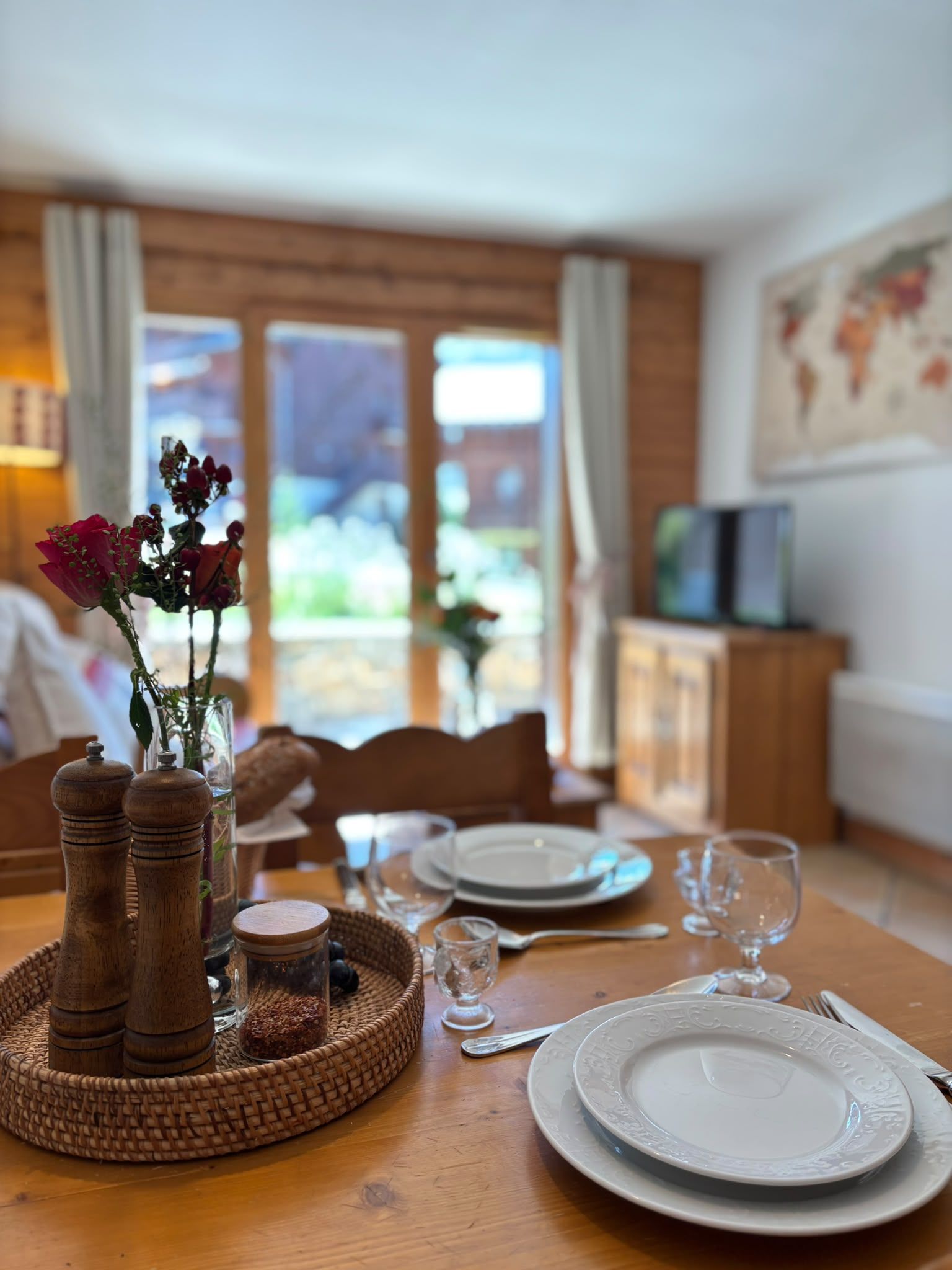 Et spisebord dækket med tallerkener, glas og en vase med blomster.