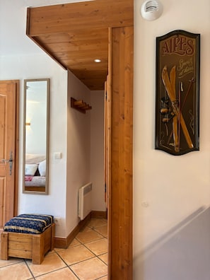 A wooden interior with a framed picture of ski equipment, a mirror, and a small bench.