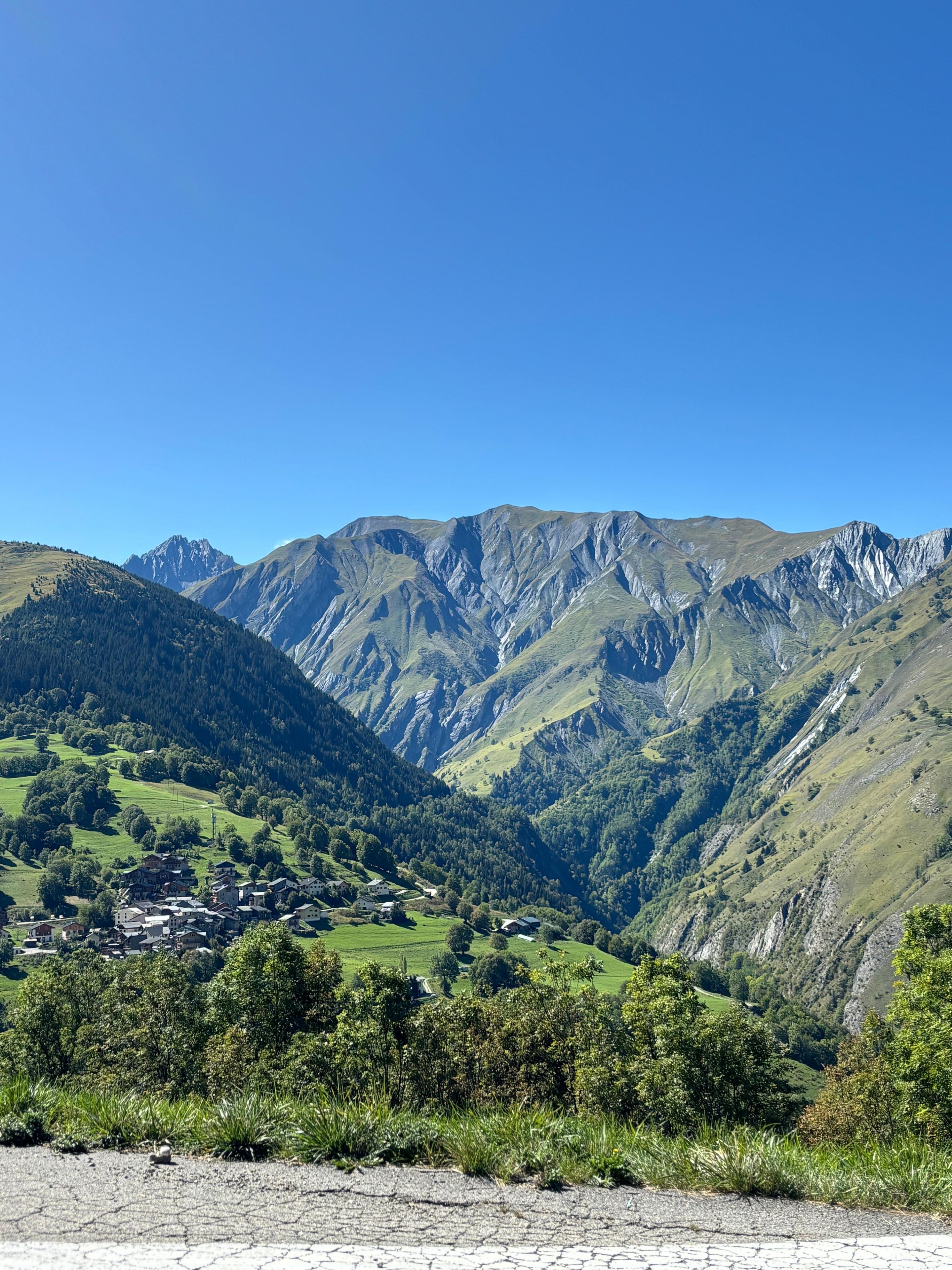Paisaje montañoso con un valle, casas y cielo despejado.
