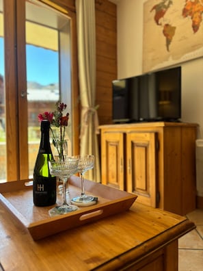 A wooden table with a bottle of champagne, glasses, and flowers.