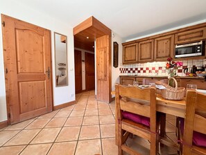 Eine Küche mit Holzausstattung, einer Mikrowelle und einem Essbereich mit Stuhl und Tisch.