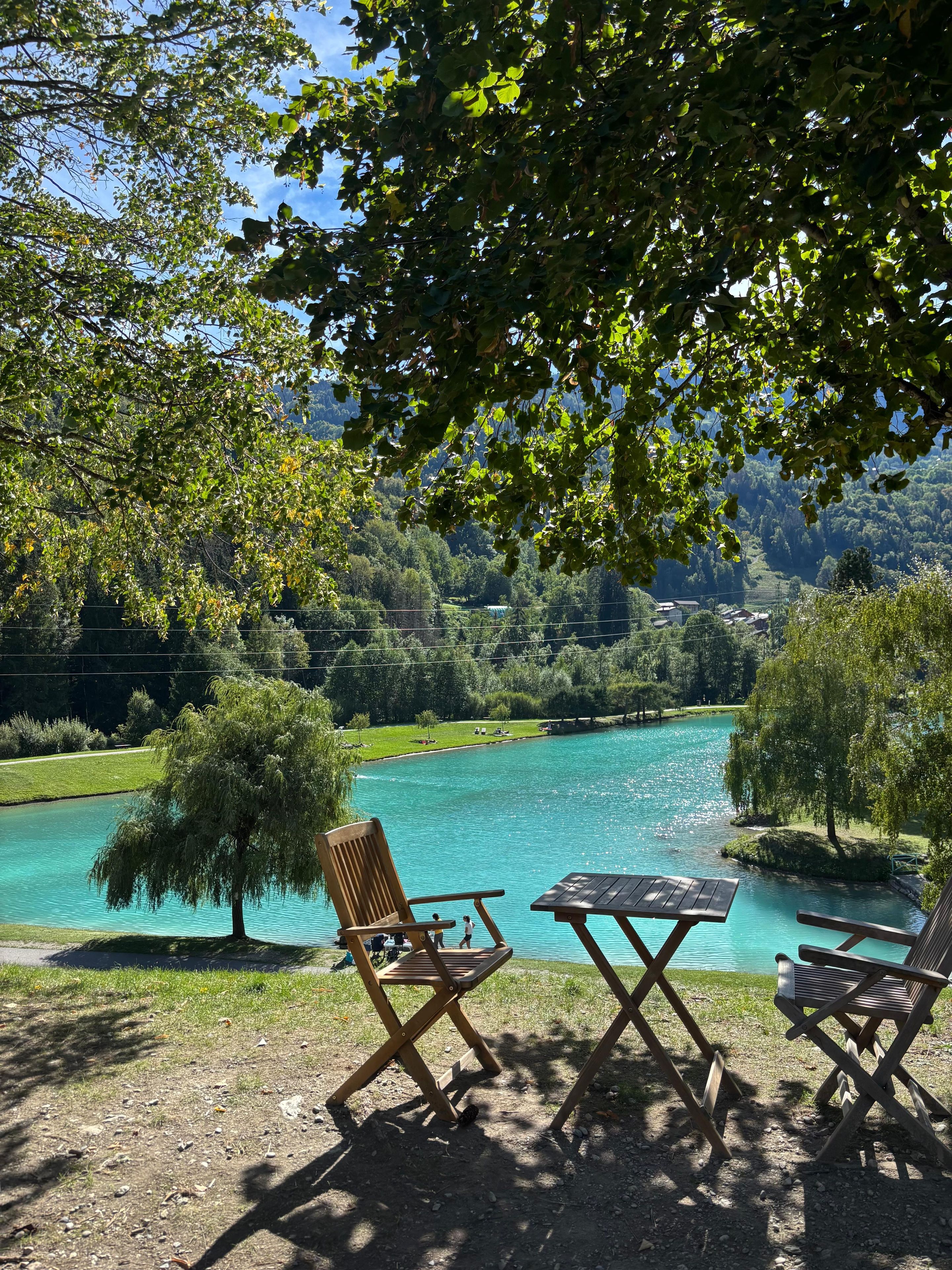 A lakeside seating area with a view of a lake and surrounding greenery.