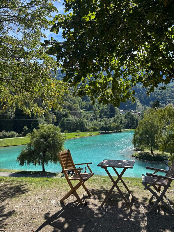 A lakeside seating area with a view of a lake and surrounding greenery.