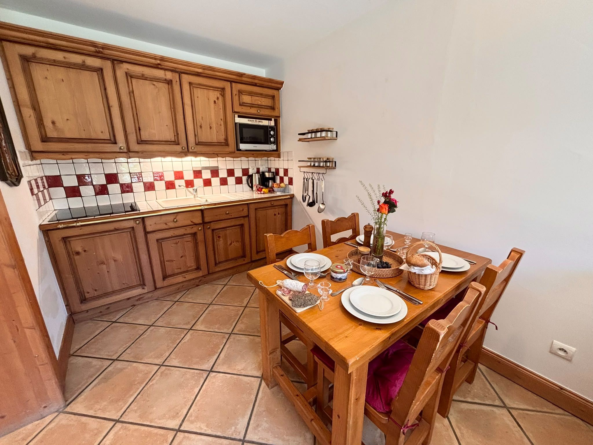 A kitchen with wooden cabinets, a tiled backsplash, and a dining table set for four.