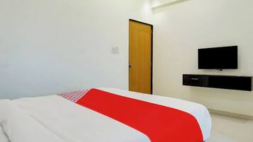 Una habitación de hotel con una cama, un televisor en la pared y una puerta.