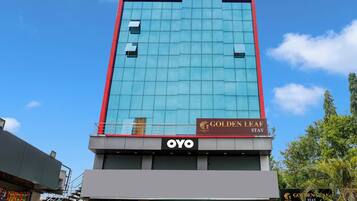 Un hotel con fachada moderna de vidrio, un letrero que dice 'Golden Leaf Stay' y la marca 'OVO' en la parte baja.
