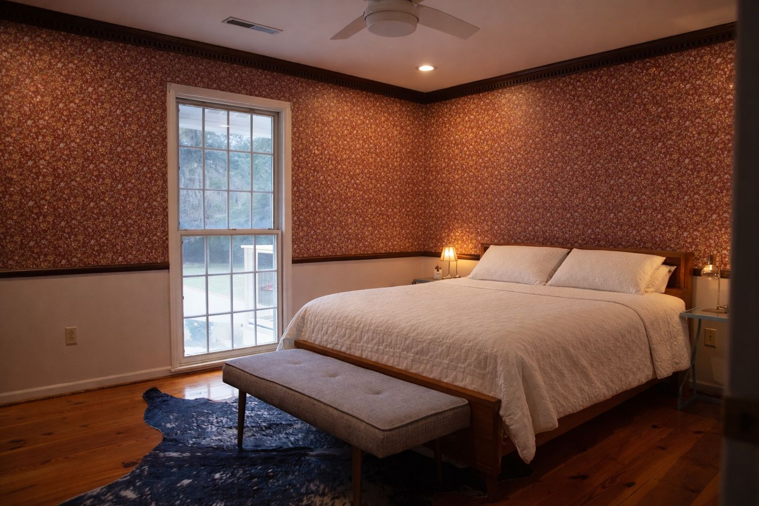 A bedroom with a large bed, a bench, a nightstand, and a window.