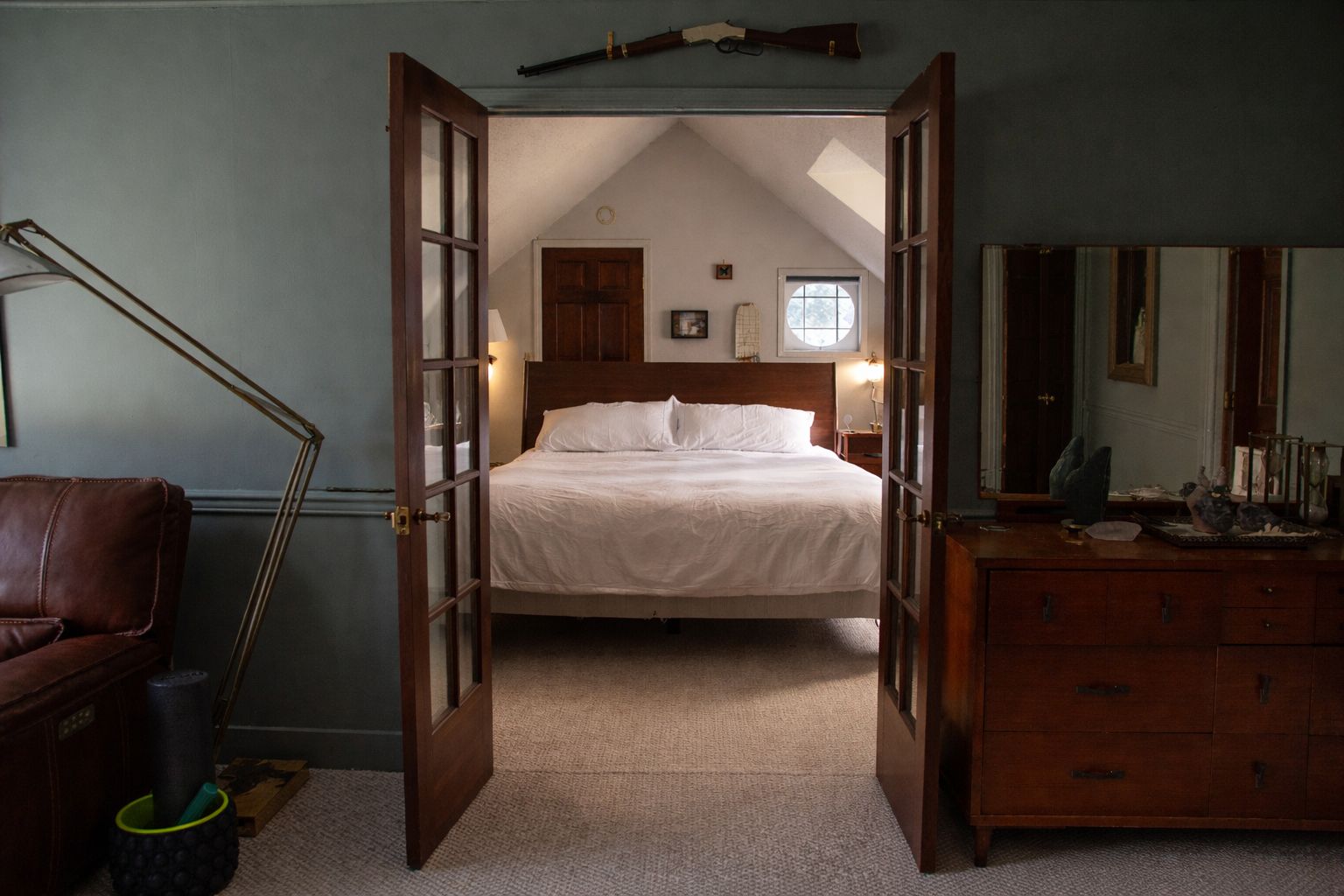 A bedroom with a bed, a dresser, a chair, and a lamp.