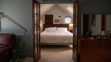 A bedroom with a bed, a dresser, a chair, and a lamp.