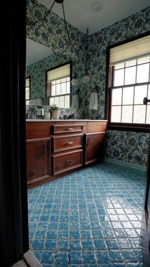 Un bagno con un mobile lavabo in legno, pavimento piastrellato e carta da parati a motivi floreali.