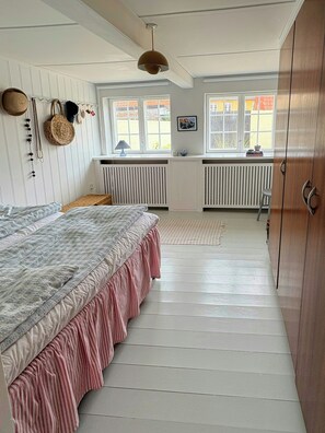 Une chambre à coucher avec un lit, un radiateur, une fenêtre et une porte.