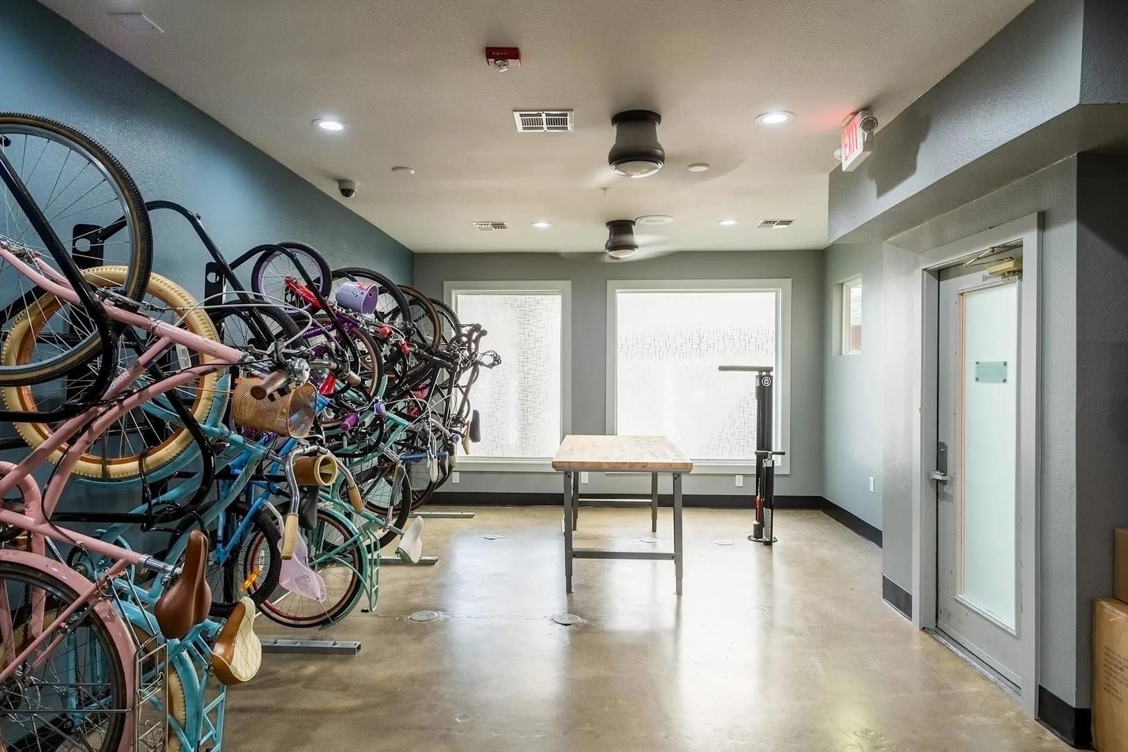 A room with a row of bicycles, a table, and a window with blinds.