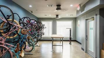 A room with a row of bicycles, a table, and a window with blinds.