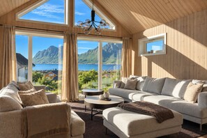 A cozy living room with a large window overlooking a mountainous landscape. - Unique Lofoten Cabin with Spectacular Ocean Views and Sauna (Nordland)
