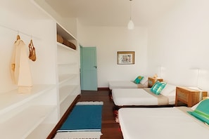 A room with two beds, a wardrobe, a door, and a framed picture on the wall.