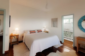 Une chambre à coucher avec un lit, des tables de chevet, une lampe, un miroir et une vue sur un balcon.
