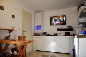 A compact kitchen with a dining table, chairs, a television mounted above the counter, and a small refrigerator. - Holiday Home 'Haus Am Stein - 2' with Mountain View, Private Terrace and Wi-Fi (Königstein)