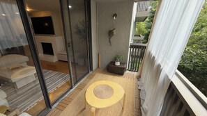 A balcony with a sliding glass door leading to a living area, a small round table, and a potted plant. - Entire Rental Unit in Downtown Palo Alto (Palo Alto)