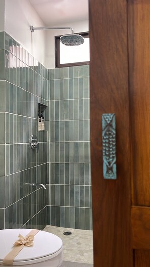 A bathroom with a shower, a toilet, and a wooden door with a decorative handle. - Casita Nimbú, A Peaceful Escape Close to Beaches (Cabo Velas)