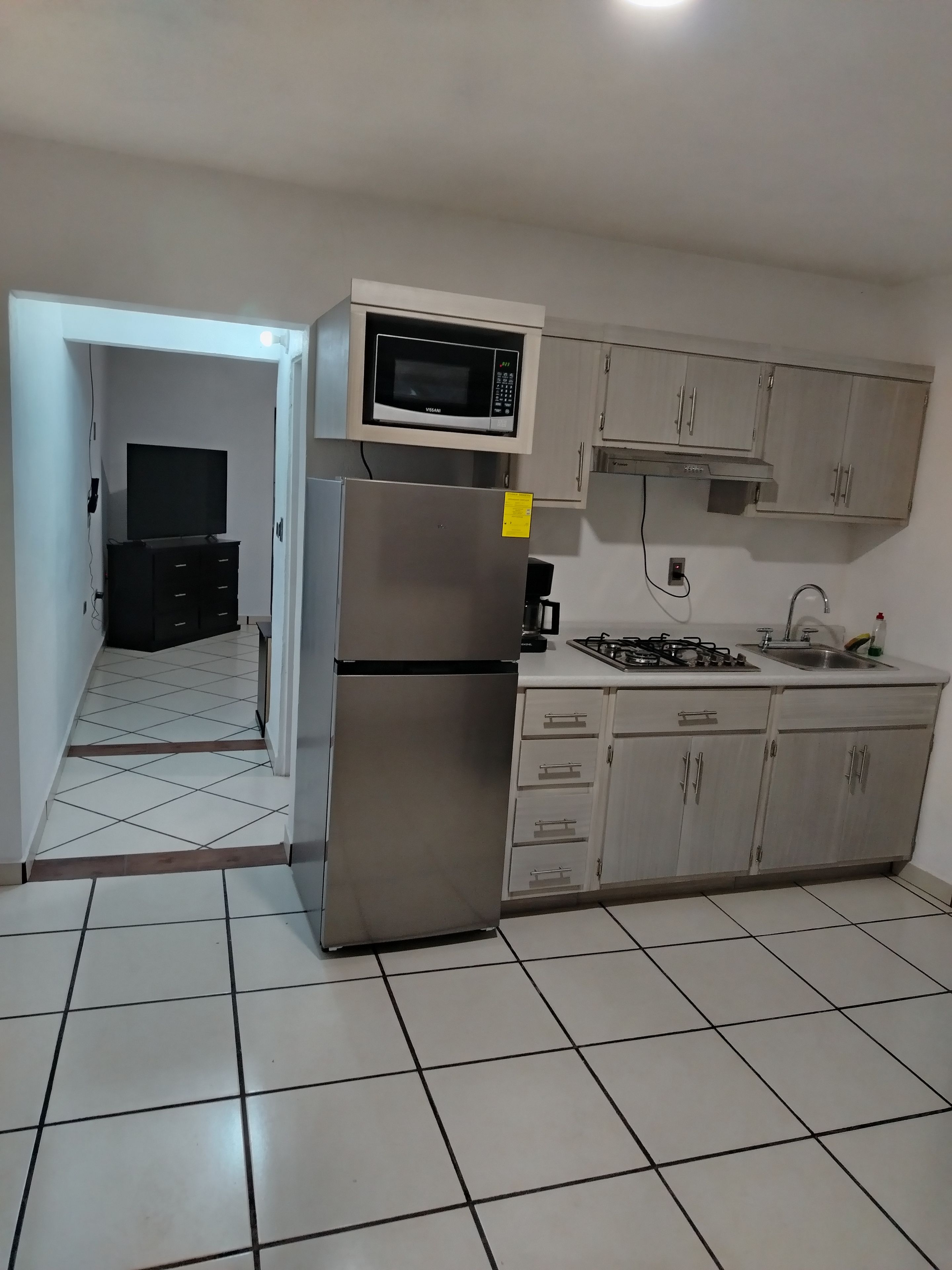 A kitchen with a refrigerator, microwave, stove, and cabinets.