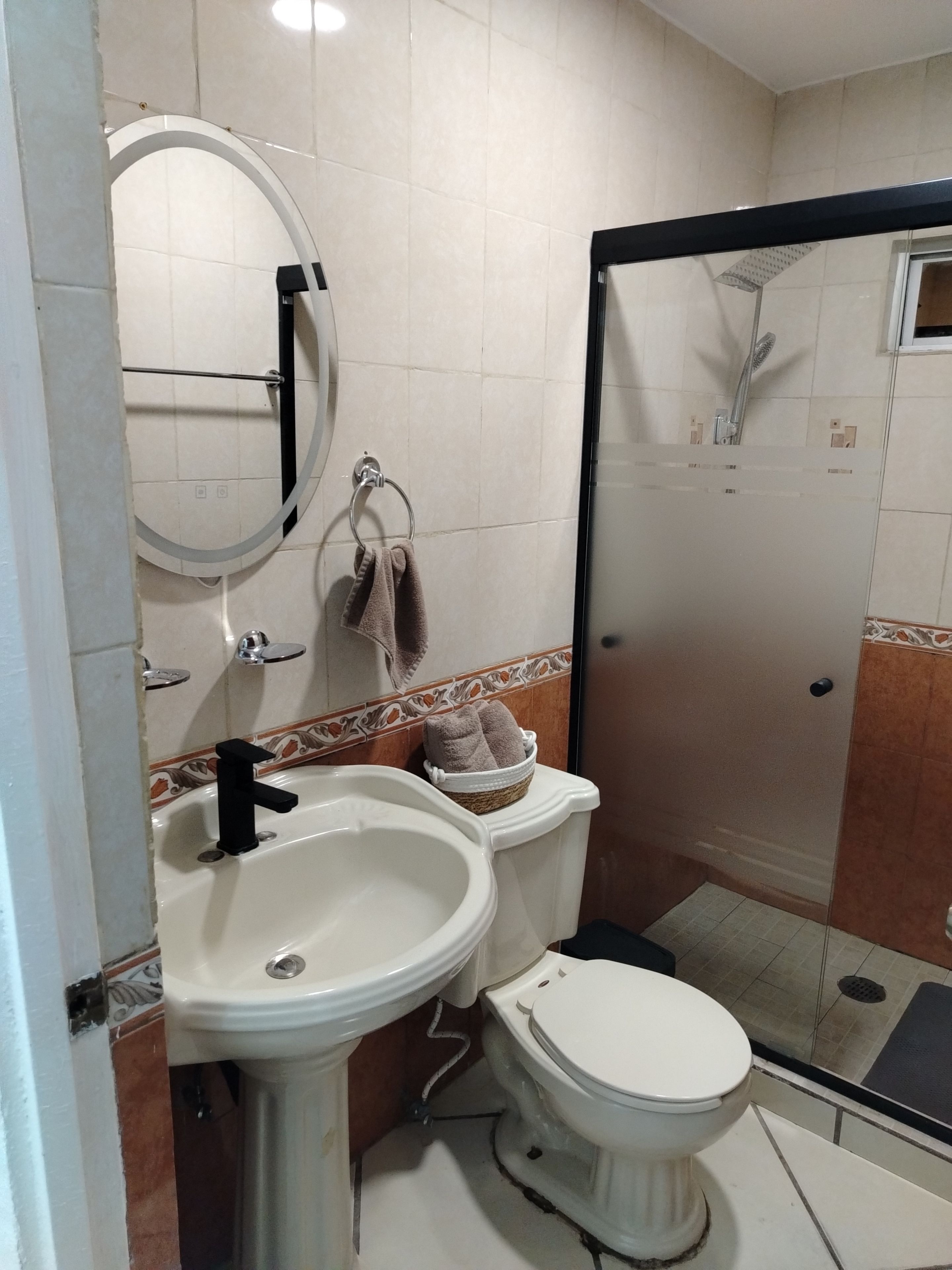 Et badeværelse med vask, toilet og bruseniche.