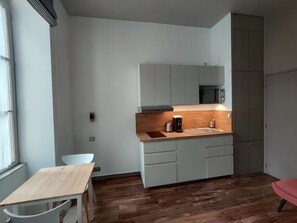 Een kleine keuken met een houten aanrecht, een ingebouwde magnetron en een spoelbak.