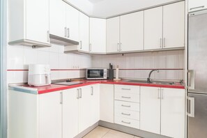 A compact kitchen with white cabinets, a red countertop, a microwave, a coffee maker, and a stainless steel refrigerator. - Home2Book Cosy Stay by La Garita Beach (La Garita)