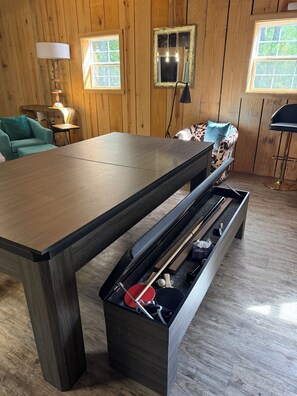 Een kamer met houten lambrisering, een grote tafel, een bank en een barkruk.