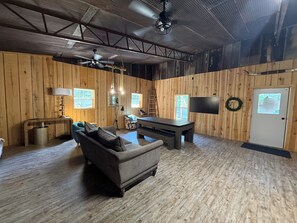 Een kamer met houten wanden, een plafondventilator, een tafel, een bank en een televisie.