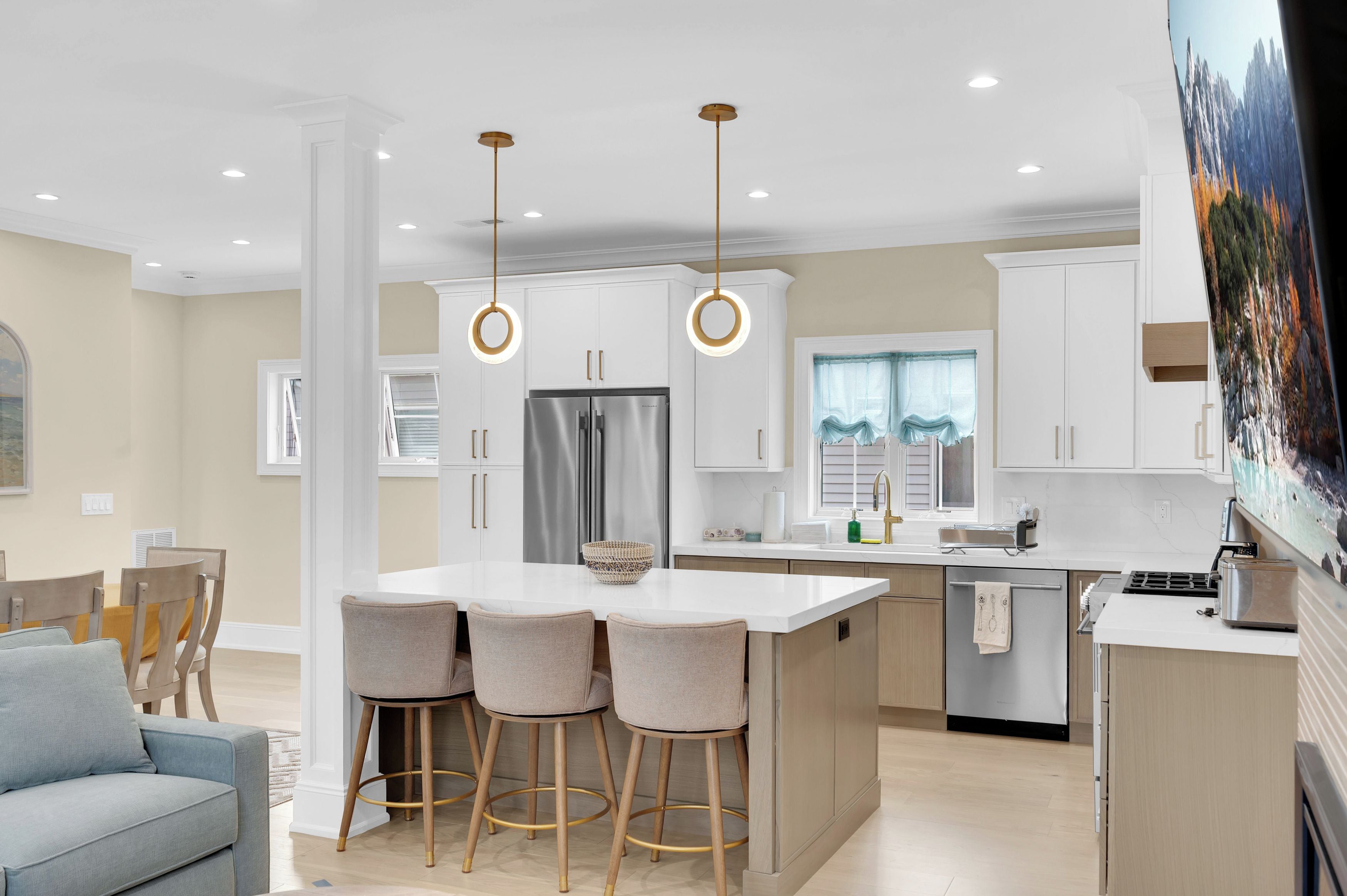 A modern kitchen with a central island, bar stools, and pendant lighting.